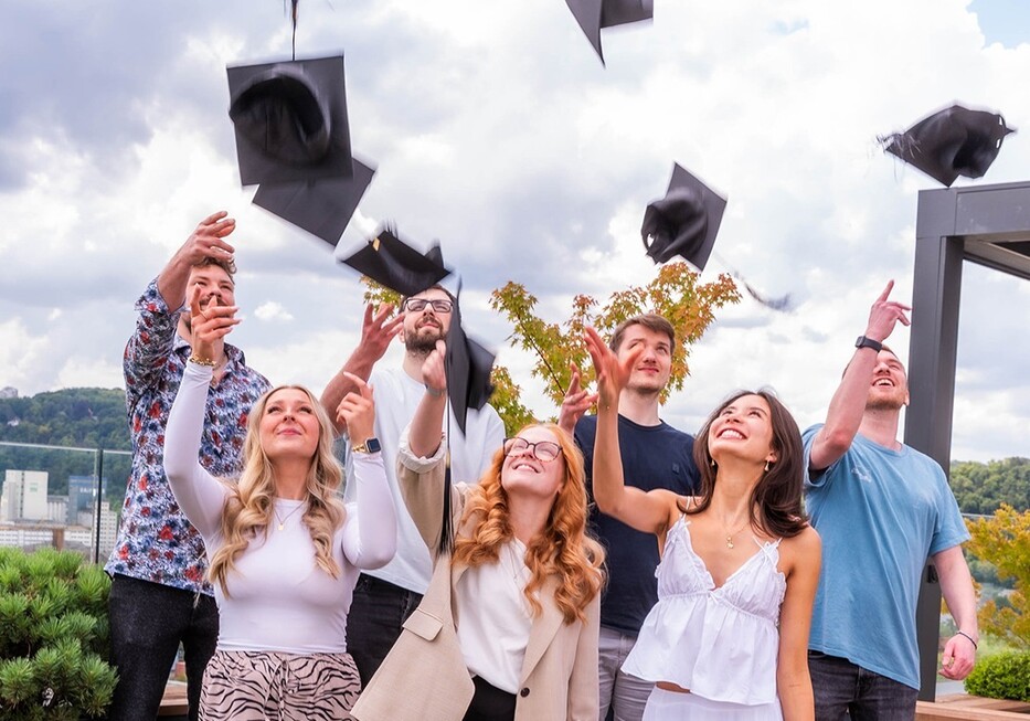 Absolventen feiern ihren Abschluss und werfen freudig ihre Hüte in die Luft